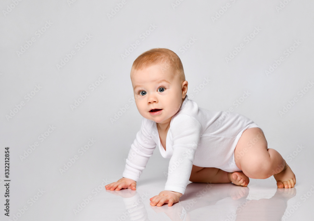 Chubby ginger little one in bodysuit, barefoot. He is sitting on floor isolated on white studio background. Close up, copy space Chubby ginger little one in bodysuit, barefoot. He is sitting on floor isolated on white studio background. Close up, copy space