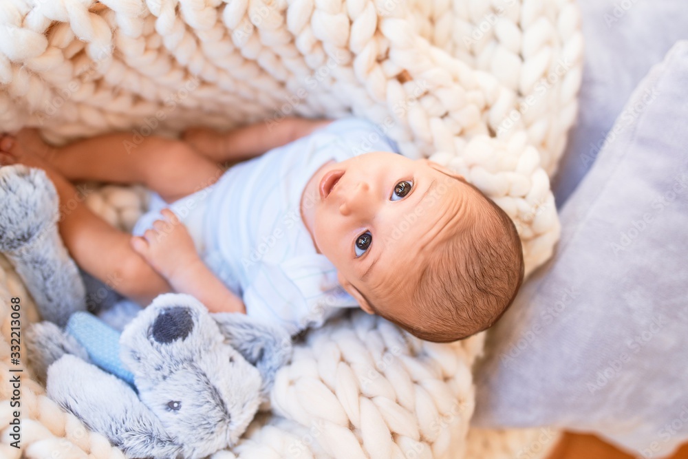 Adorable baby lying down over blanket on the floor at home. Newborn relaxing and resting comfortable with teddy bear Adorable baby lying down over blanket on the floor at home. Newborn relaxing and resting comfortable with teddy bear