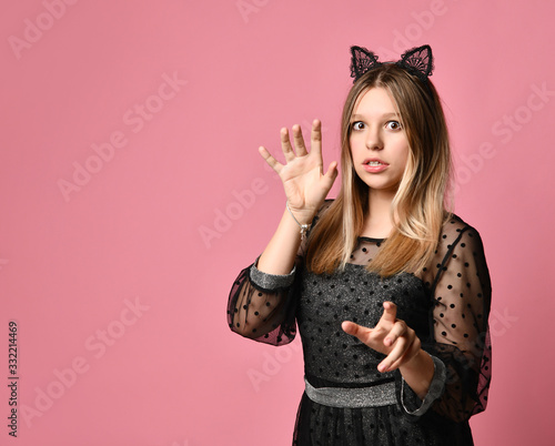 Teen girl in black dress, headband in form of cat ears, bracelet. Acting like...