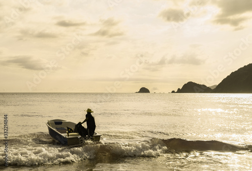 An unidentified man drives boat during sunset in Praia Do Sono, Paraty, Brazil. © Samponi
