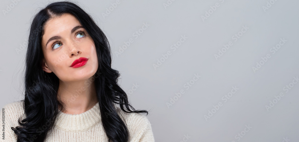 Young woman in a thoughtful pose on a gray background Young woman in a thoughtful pose on a gray background