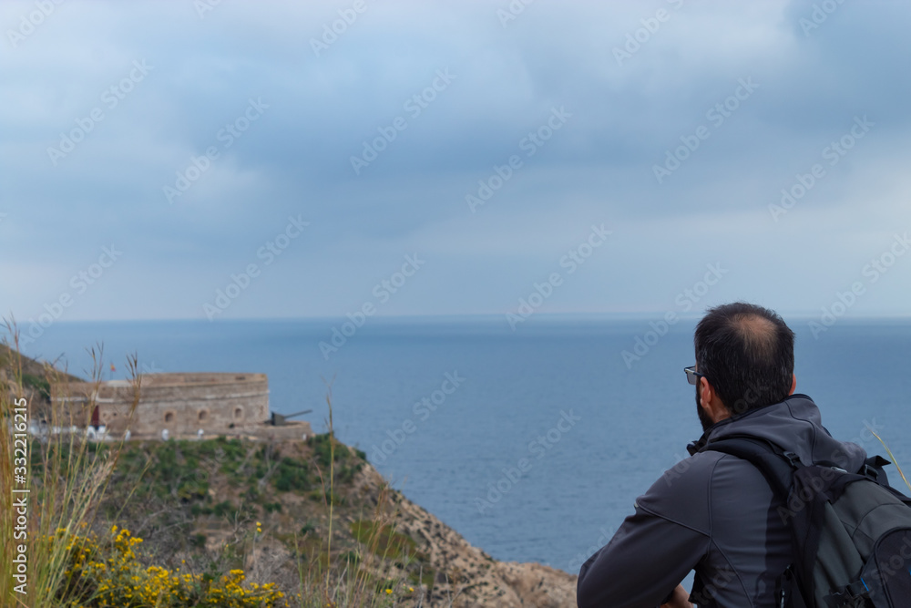 Seated man looking at a fortification in the distance