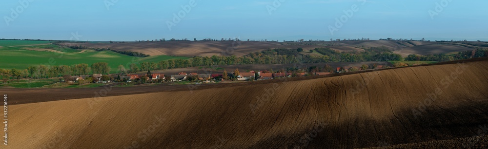 A very large panorama of the beautifully undulating plowed Moravian fields with the village in the background