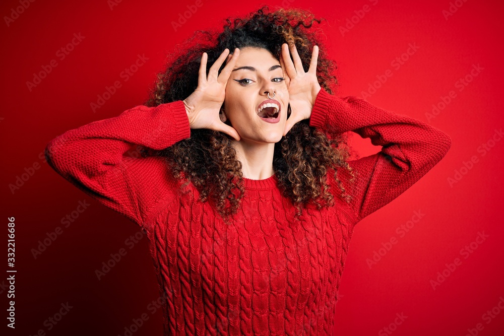 Young beautiful woman with curly hair and piercing wearing casual red sweater Smiling cheerful playing peek a boo with hands showing face. Surprised and exited Young beautiful woman with curly hair and piercing wearing casual red sweater Smiling cheerful playing peek a boo with hands showing face. Surprised and exited
