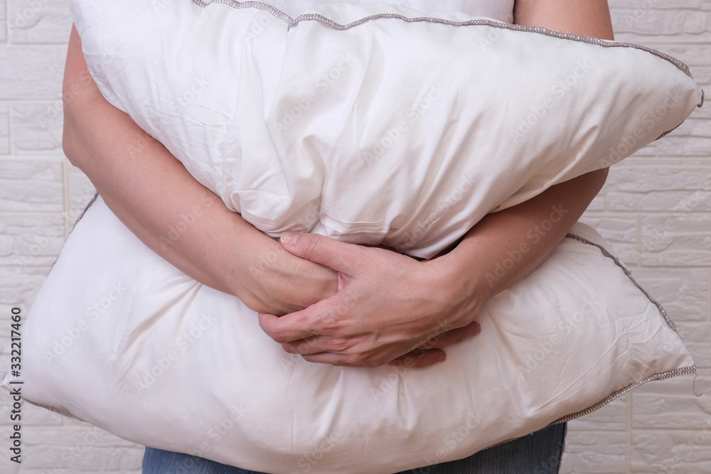 Woman holding white fluffy pillow in hands, hugging a pillow - sleeping and resting concept Woman holding white fluffy pillow in hands, hugging a pillow - sleeping and resting concept