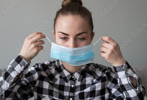 Girl with medical mask to protect her from virus. Coronavirus pandemic. Woman with mask standing . People being hospitalized, diagnosed, often put in carantine (isolation) to stop spreading Corona. photo