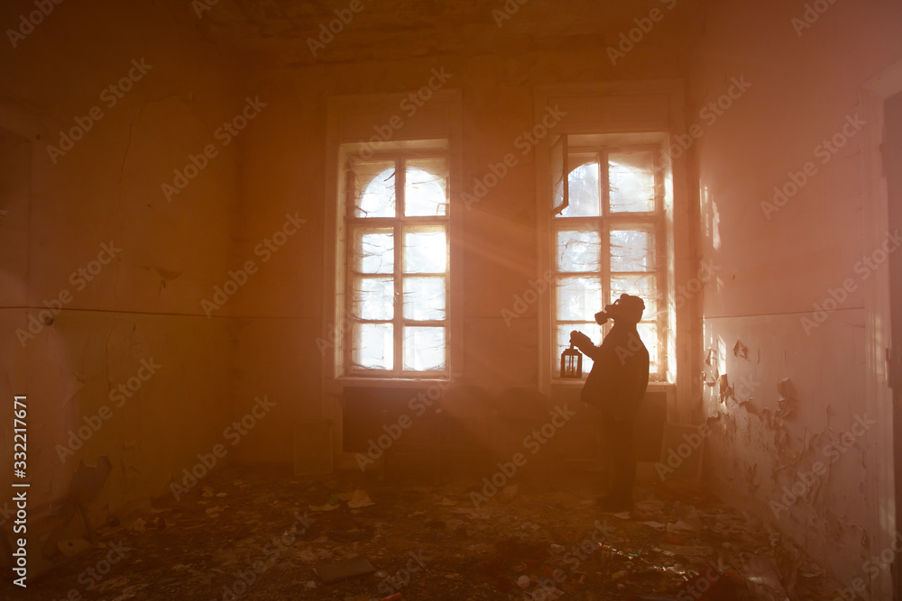 Dramatic portrait of a woman wearing a gas mask in a ruined building.