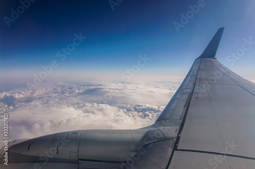 Wing of an airplane flying above the clouds. people looks at the sky from the window of the plane, using air transport to travel. photo