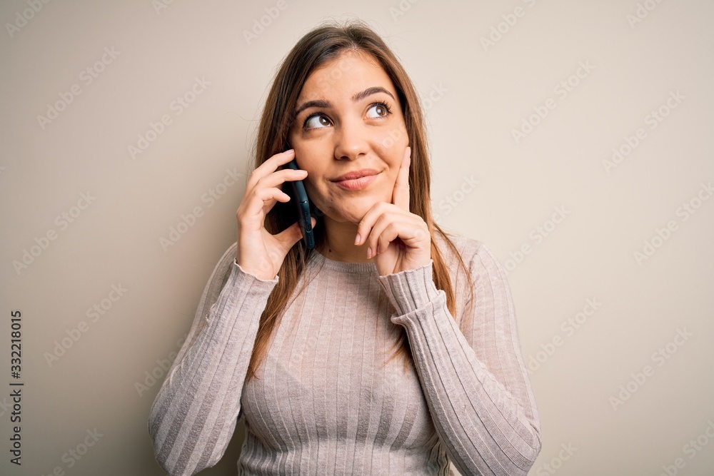 Young woman having a conversation speaking on smartphone over isolated background serious face thinking about question, very confused idea Young woman having a conversation speaking on smartphone over isolated background serious face thinking about question, very confused idea