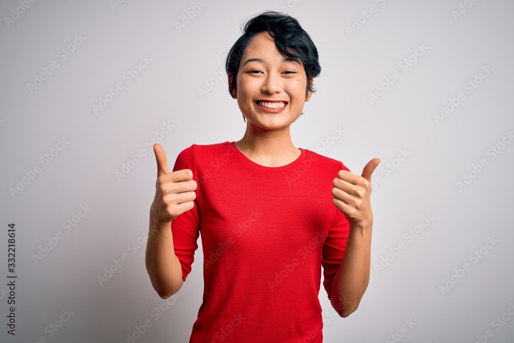 Young beautiful asian girl wearing casual red t-shirt standing over isolated white background success sign doing positive gesture with hand, thumbs up smiling and happy. Cheerful expression and winner Young beautiful asian girl wearing casual red t-shirt standing over isolated white background success sign doing positive gesture with hand, thumbs up smiling and happy. Cheerful expression and winner