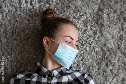 Girl with medical mask to protect her from virus. Coronavirus pandemic. Woman with mask standing . People being hospitalized, diagnosed, often put in carantine (isolation) to stop spreading Corona. photo