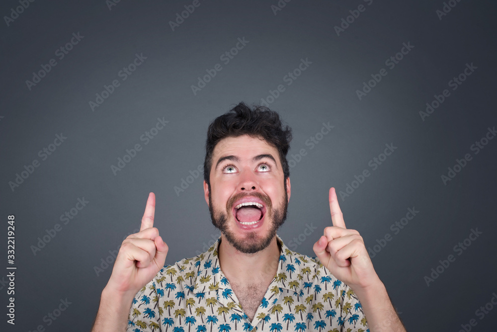Charming carefree man with positive expression, points up with both index fingers, dressed in casual clothing, has broad intrested smile, isolated over pink background. Look there, please†Charming carefree man with positive expression, points up with both index fingers, dressed in casual clothing, has broad intrested smile, isolated over pink background. Look there, pleaseâ€