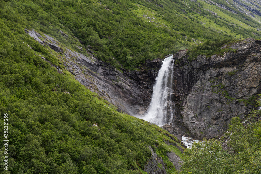 waterfall in a northern mountainous landscape with abundant green vegetation waterfall in a northern mountainous landscape with abundant green vegetation
