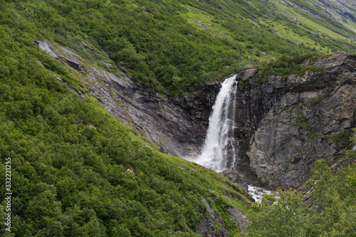 waterfall in a northern mountainous landscape with abundant green vegetation