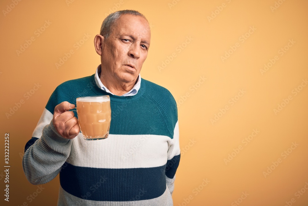 Senior handsome man drinking jar of beer standing over isolated yellow background looking sleepy and tired, exhausted for fatigue and hangover, lazy eyes in the morning. Senior handsome man drinking jar of beer standing over isolated yellow background looking sleepy and tired, exhausted for fatigue and hangover, lazy eyes in the morning.