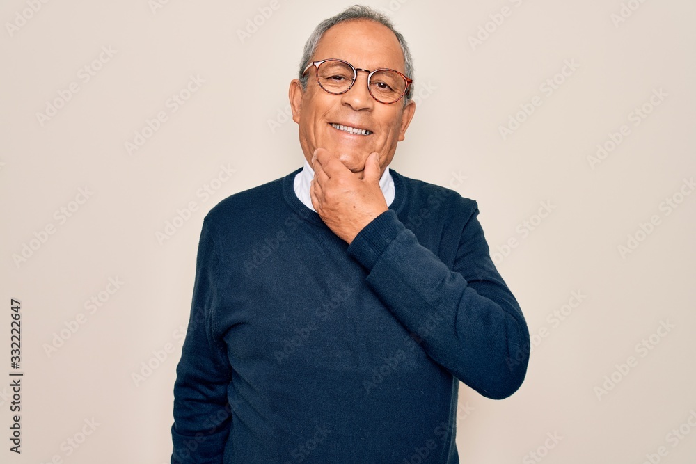 Senior handsome grey-haired man wearing sweater and glasses over isolated white background looking confident at the camera smiling with crossed arms and hand raised on chin. Thinking positive. Senior handsome grey-haired man wearing sweater and glasses over isolated white background looking confident at the camera smiling with crossed arms and hand raised on chin. Thinking positive.