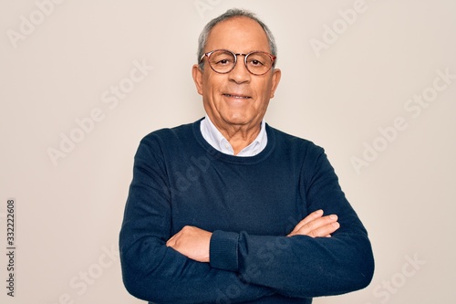 Senior handsome grey-haired man wearing sweater and glasses over isolated white background happy face smiling with crossed arms looking at the camera. Positive person.