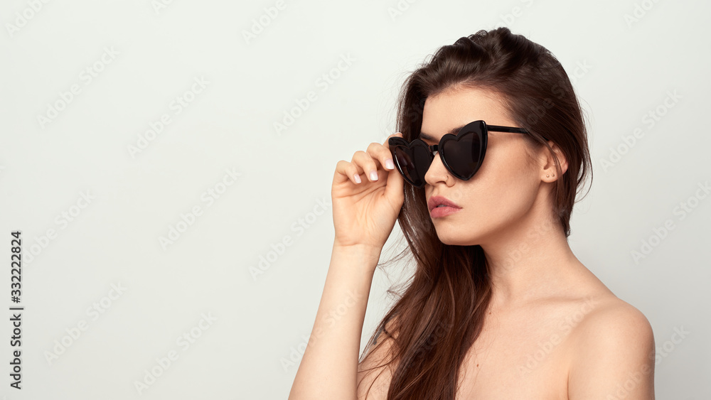 beautiful young girl with brown hair in fashionable glasses posing on a white background with bare shoulders, empty space for text beautiful young girl with brown hair in fashionable glasses posing on a white background with bare shoulders, empty space for text