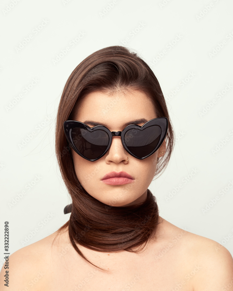 beautiful young girl with brown hair in fashionable glasses posing on a white background with bare shoulders, empty space for text beautiful young girl with brown hair in fashionable glasses posing on a white background with bare shoulders, empty space for text