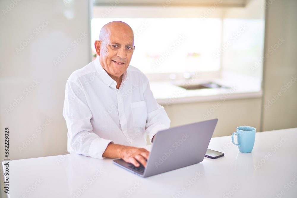 Senior handsome man smiling happy and confident. Sitting using laptop and drinking cup of coffee at home Senior handsome man smiling happy and confident. Sitting using laptop and drinking cup of coffee at home