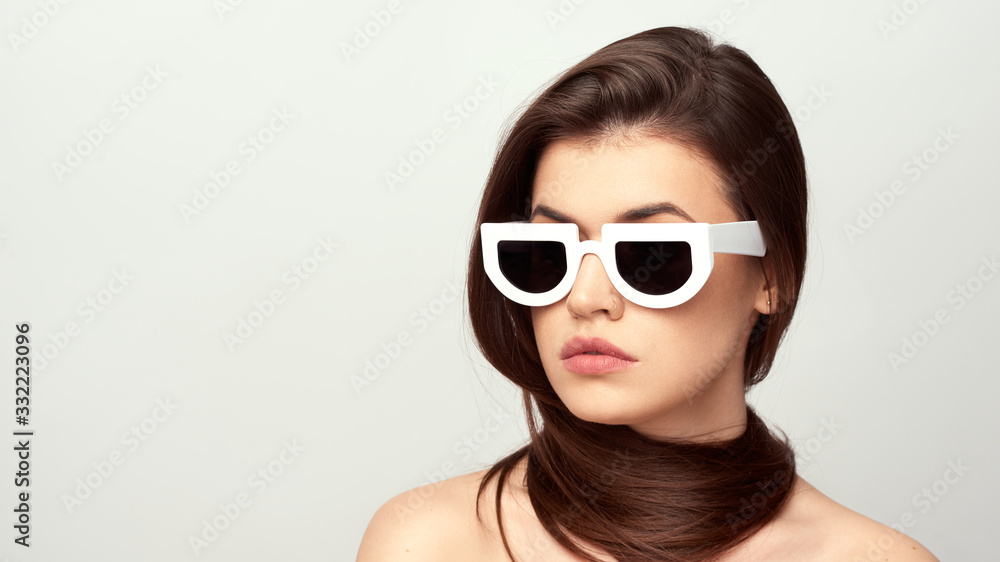beautiful young girl with brown hair in fashionable glasses posing on a white background with bare shoulders, empty space for text beautiful young girl with brown hair in fashionable glasses posing on a white background with bare shoulders, empty space for text