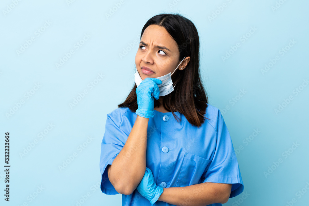 Surgeon woman over isolated blue background having doubts Surgeon woman over isolated blue background having doubts