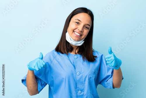 Surgeon woman over isolated blue background giving a thumbs up gesture