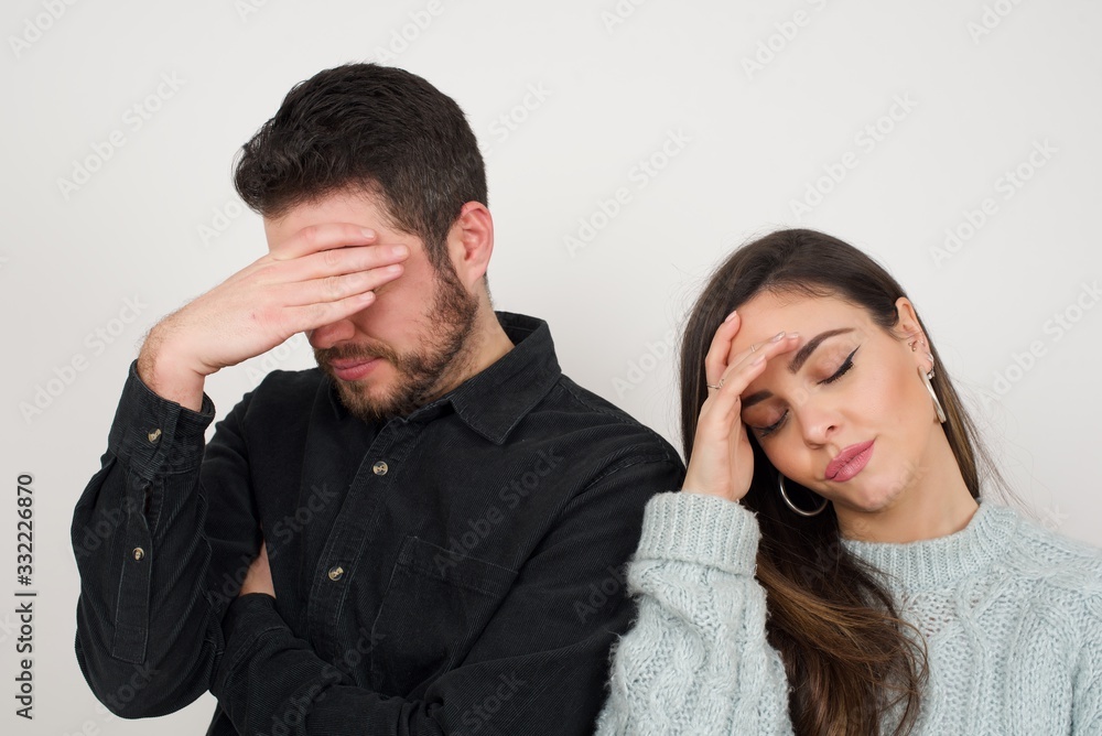 Indoor portrait of beautiful couple with stylish haircut, wearing casual clothes, making facepalm gesture while smiling, standing over gray background amazed with stupid situation. Indoor portrait of beautiful couple with stylish haircut, wearing casual clothes, making facepalm gesture while smiling, standing over gray background amazed with stupid situation.