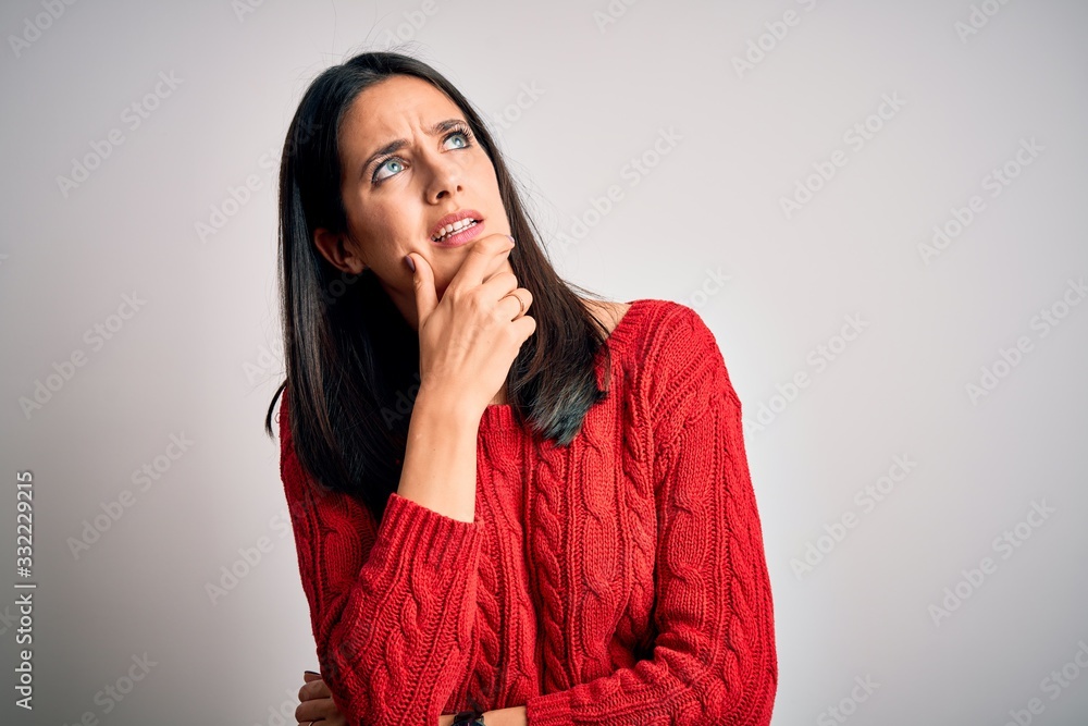 Young brunette woman with blue eyes wearing casual sweater over isolated white background Thinking worried about a question, concerned and nervous with hand on chin Young brunette woman with blue eyes wearing casual sweater over isolated white background Thinking worried about a question, concerned and nervous with hand on chin