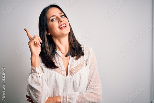 Young brunette woman with blue eyes wearing casual t-shirt over isolated white background with a big smile on face, pointing with hand and finger to the side looking at the camera.