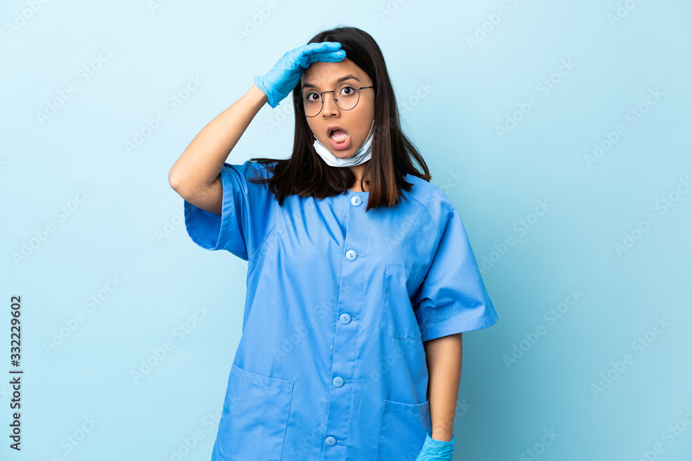 Surgeon woman over isolated blue background doing surprise gesture while looking to the side Surgeon woman over isolated blue background doing surprise gesture while looking to the side