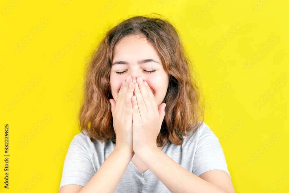 Portrait of pretty curly cheerful teenager girl laughing to the palms of hands Portrait of pretty curly cheerful teenager girl laughing to the palms of hands