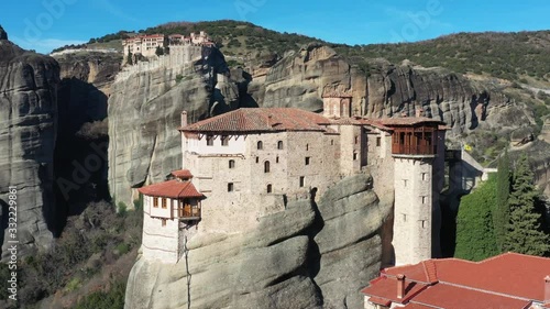 Aerial video of monastery Rousanou and Varlaam, breathtaking picturesque valley and landmark canyon of Meteora at sunset, Kalambaka, mountains of Greece, video by drone, a lot of buses with tourists photo