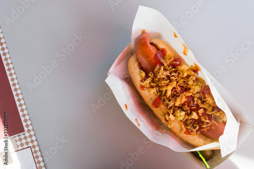 Tasty hot dog with grilled sausage, salt cucumber, mustard and crisps