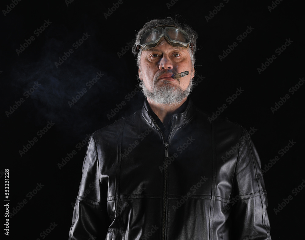 studio portrait of an old biker with a cigar on a black background