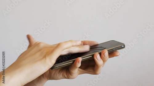 Female hands cleaning smartphone with sanitizer gel over bright gray background