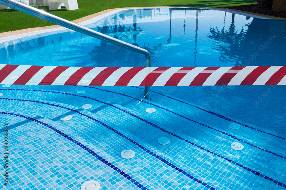 Fototapeta premium Red White warning tape pole fencing is protects for No entry (in the pool) . Ban on visiting public places (swimming pools, sports clubs). Ban on travel to resorts in other countries due to epidemic