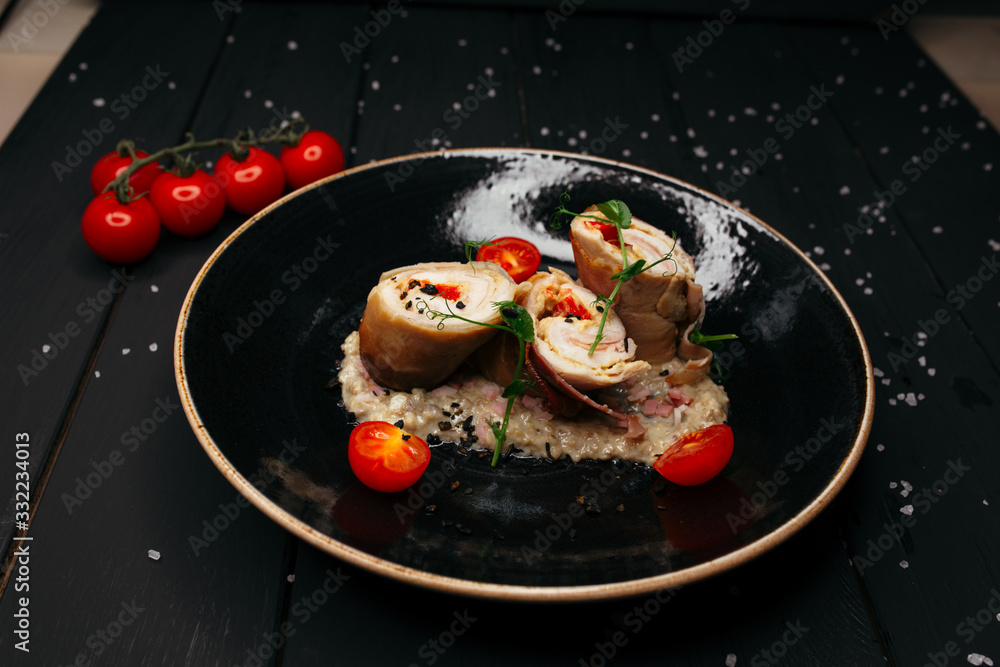 Slices of delicious meatloaf laid out in bacon sauce. Black plate decorated with cherry tomatoes. Dish on a black wooden table. Slices of delicious meatloaf laid out in bacon sauce. Black plate decorated with cherry tomatoes. Dish on a black wooden table.