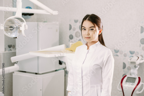cheerful female dentist smiling in her office. dentistry student standing in a dental treatment room