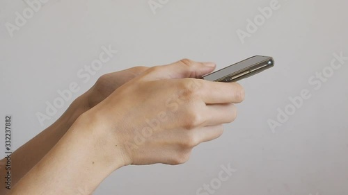Female hands using mobile phone and scrolling against gray wall background