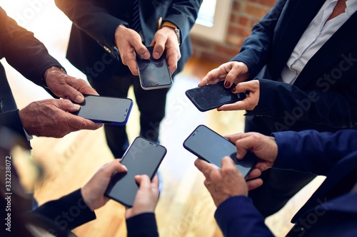 Group of business workers standing on a circle using smartphone together at the office.