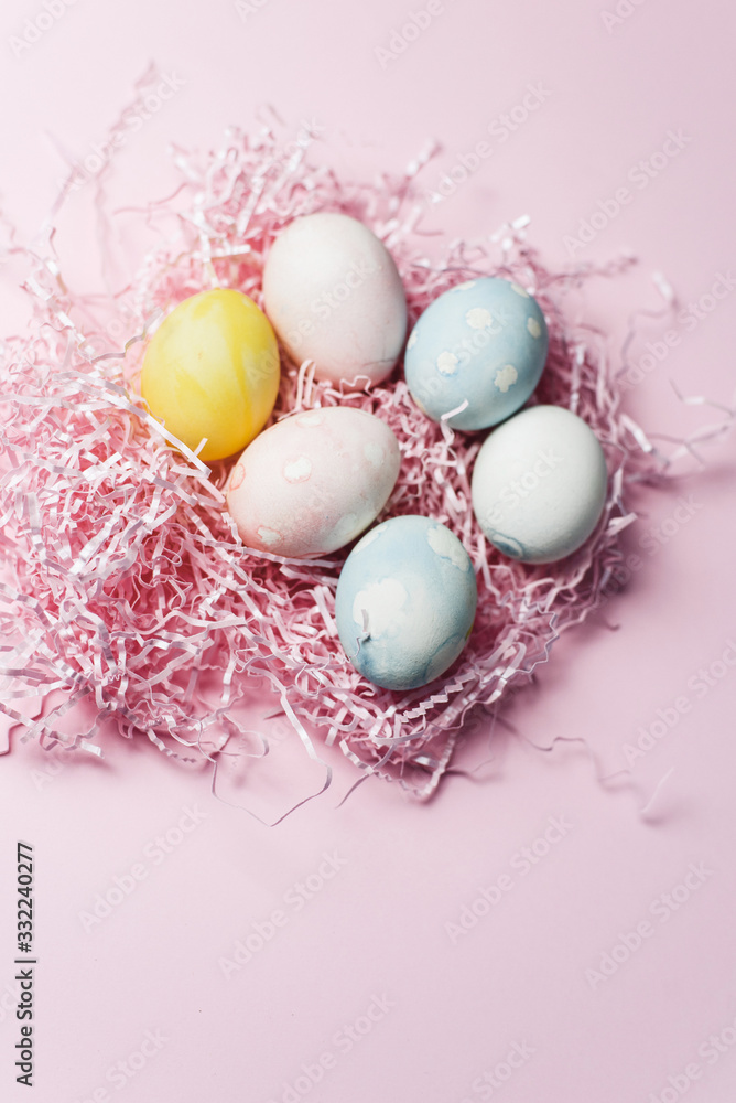 Painted eggs in pastel colors on a pink paper filler and background. Modern easter holiday template