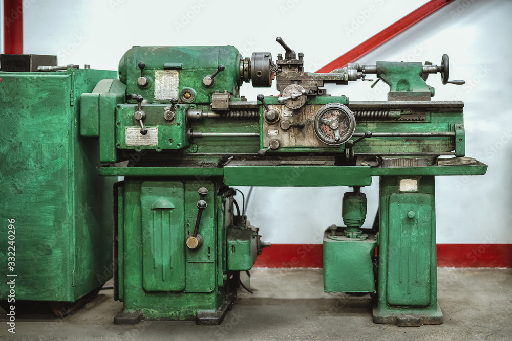 The old lathe is painted green. Small metal processing shop