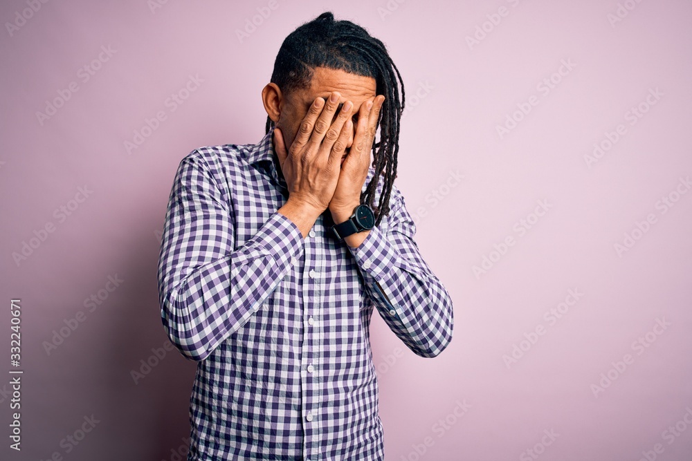 Young handsome african american afro man with dreadlocks wearing casual shirt with sad expression covering face with hands while crying. Depression concept. Young handsome african american afro man with dreadlocks wearing casual shirt with sad expression covering face with hands while crying. Depression concept.