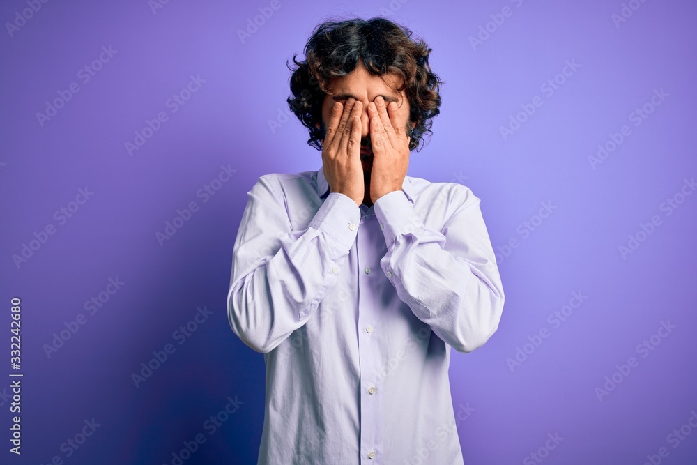 Young handsome business man with beard wearing shirt standing over purple background rubbing eyes for fatigue and headache, sleepy and tired expression. Vision problem Young handsome business man with beard wearing shirt standing over purple background rubbing eyes for fatigue and headache, sleepy and tired expression. Vision problem