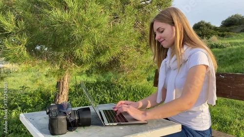 Young pretty female freelance typing message by laptop at the hill top