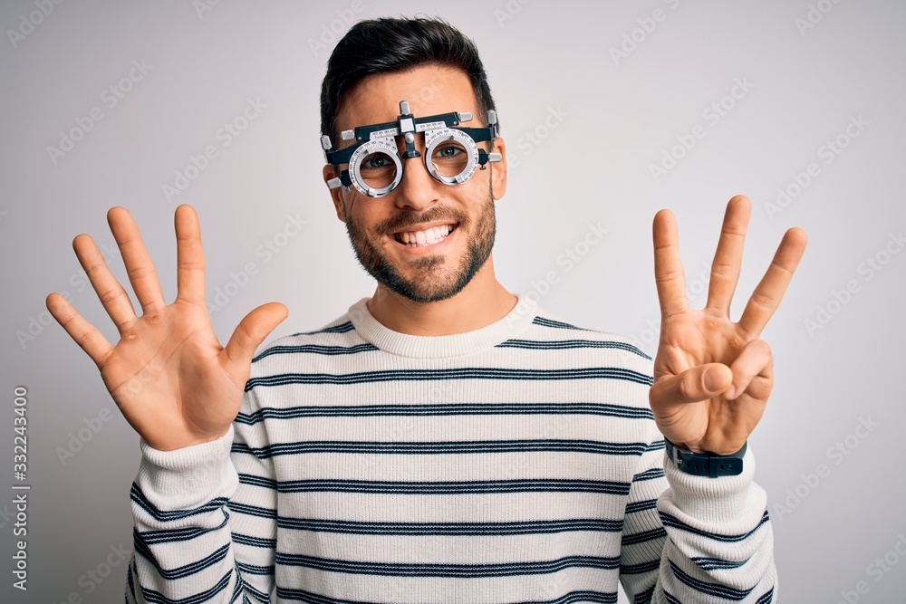 Naklejka premium Young handsome man with beard wearing optometry glasses over isolated white background showing and pointing up with fingers number eight while smiling confident and happy.