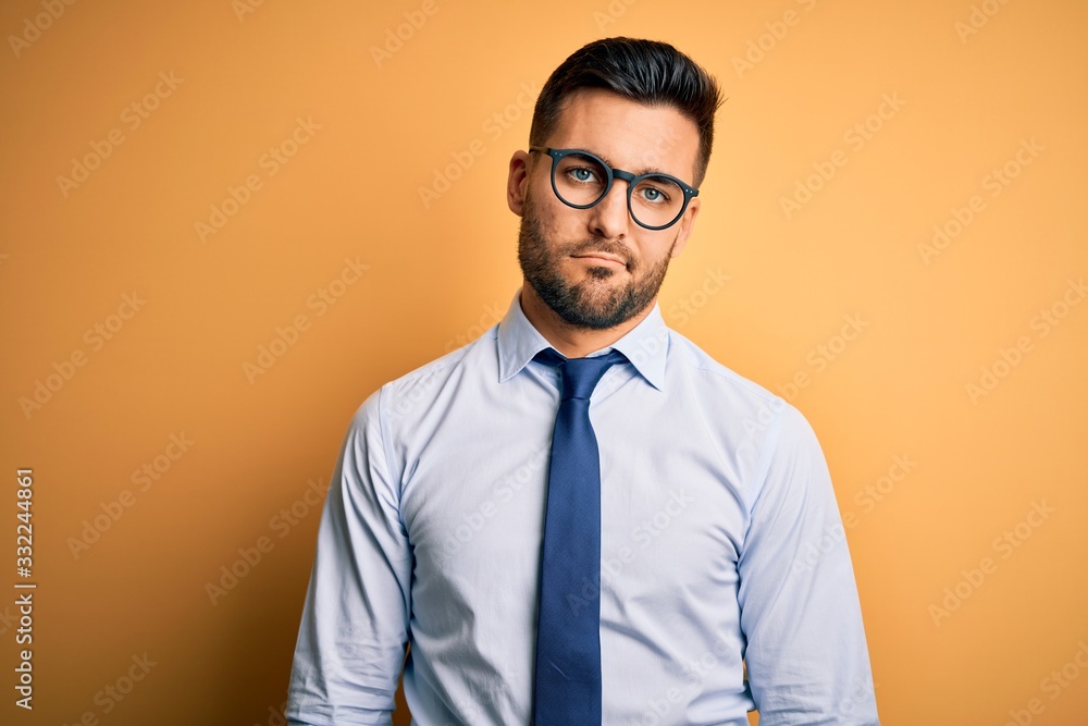 Young handsome businessman wearing tie and glasses standing over yellow background looking sleepy and tired, exhausted for fatigue and hangover, lazy eyes in the morning. Young handsome businessman wearing tie and glasses standing over yellow background looking sleepy and tired, exhausted for fatigue and hangover, lazy eyes in the morning.