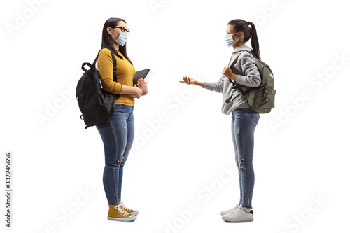 Young female students wearing protective medical masks and having a conversation