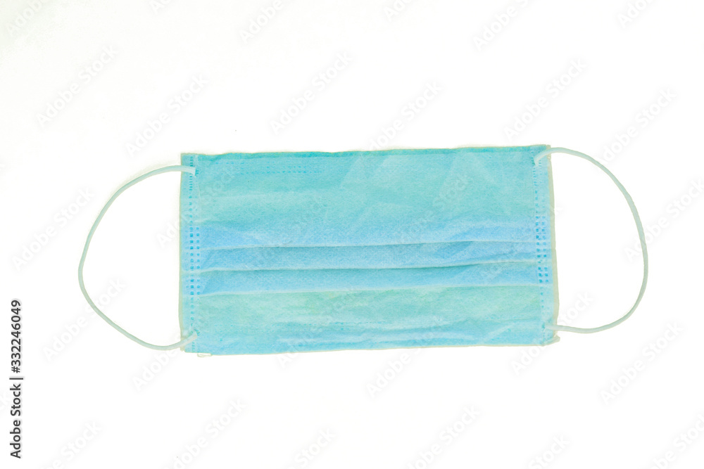 Surgical mask with white rubber straps isolated on a light white paper background Surgical mask with white rubber straps isolated on a light white paper background